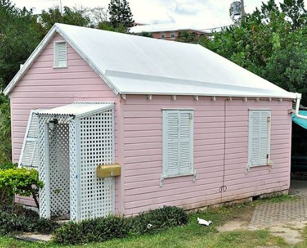 In this image is a pink she shed reused from an old shed with a pink pastel finish